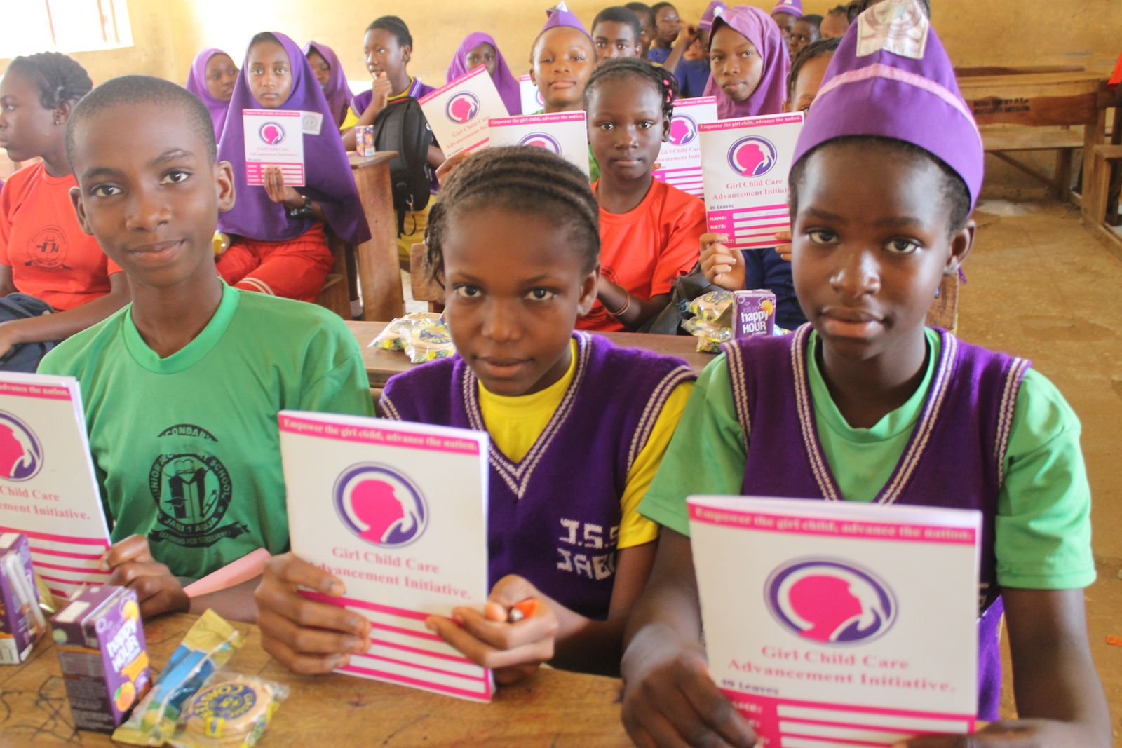 Students holding GCCAI exercise books in a classroom