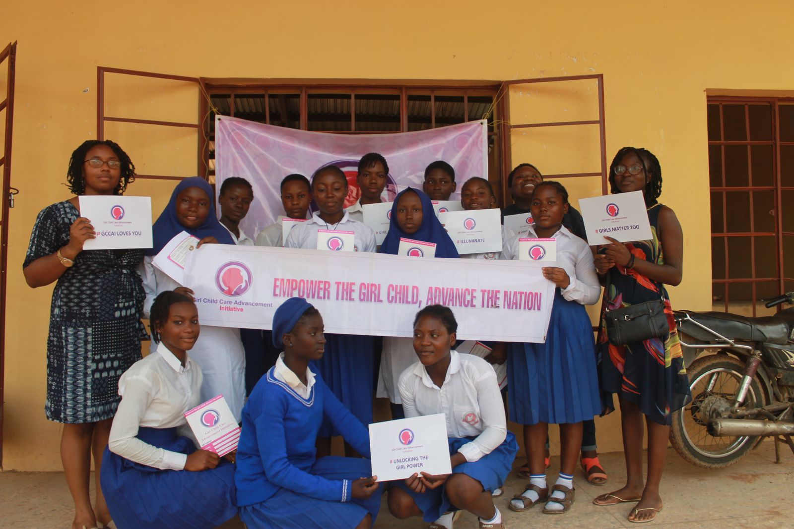 Students and GCCAI volunteers holding a banner that reads Empower the girl child, advance the nation
